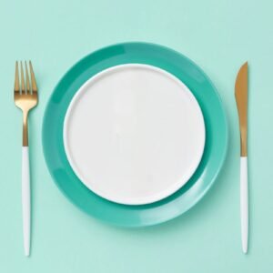 Teal plate set with fork and knife on a matching background. Minimalist and modern design.