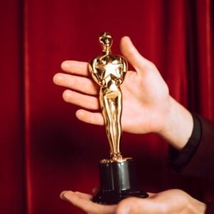 Elegant golden figurine trophy presented against a vibrant red curtain backdrop.