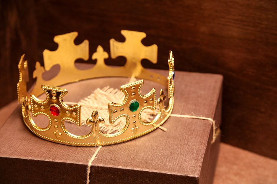 A luxurious gold crown with gems sits atop a brown gift box in a rustic setting.